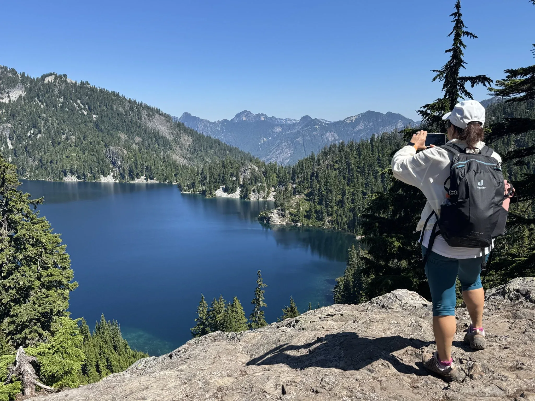 Hiker taking a photo of Snow Lake from a vantage point.