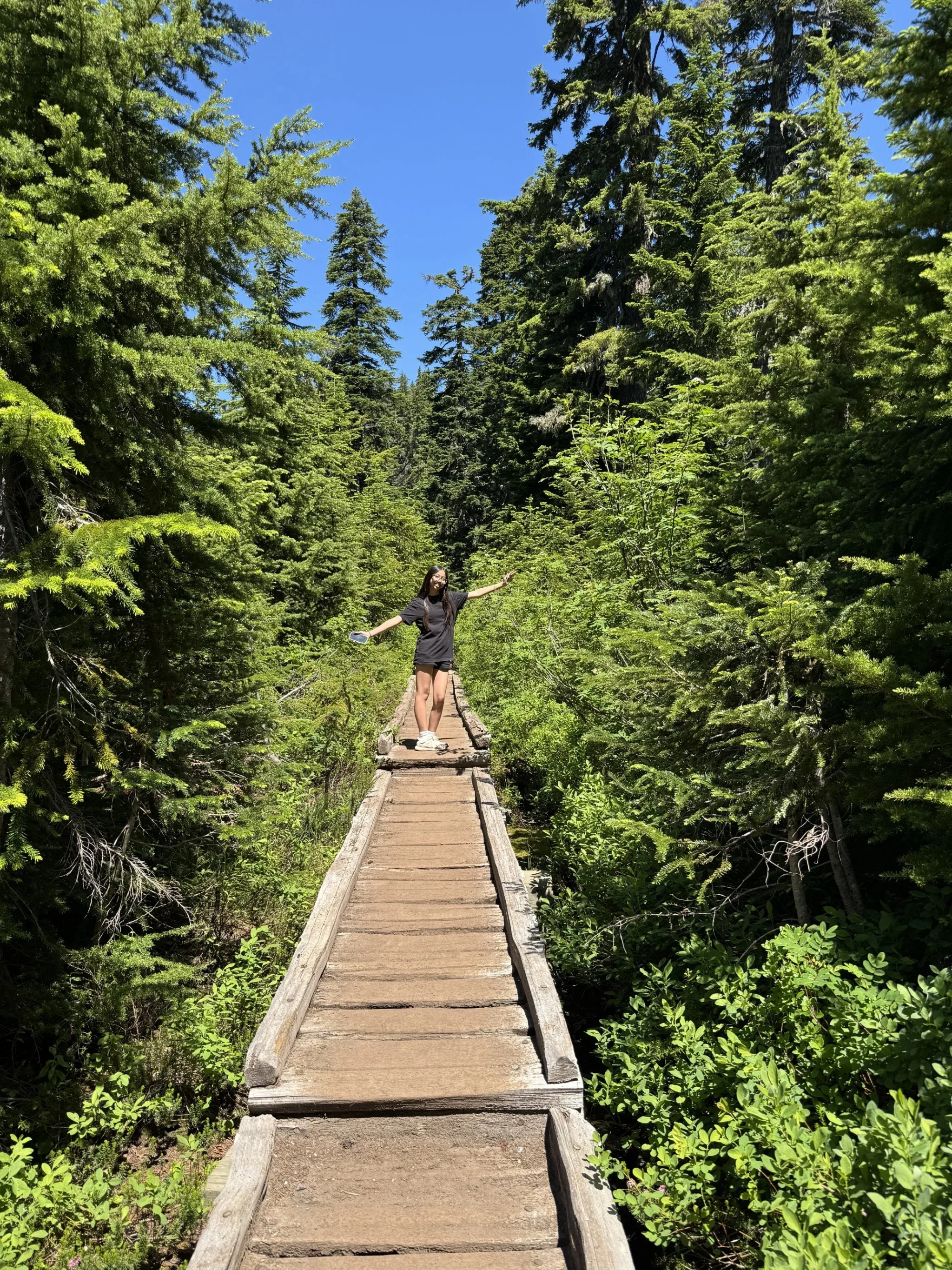 Leah with arms extended on a wooden path.